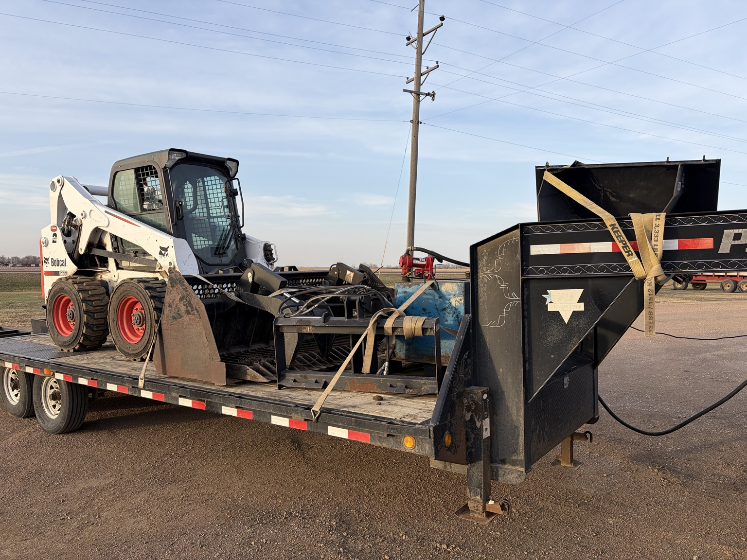 Side view of SS Stump Grinding trailer setup with Bobcat and attachments