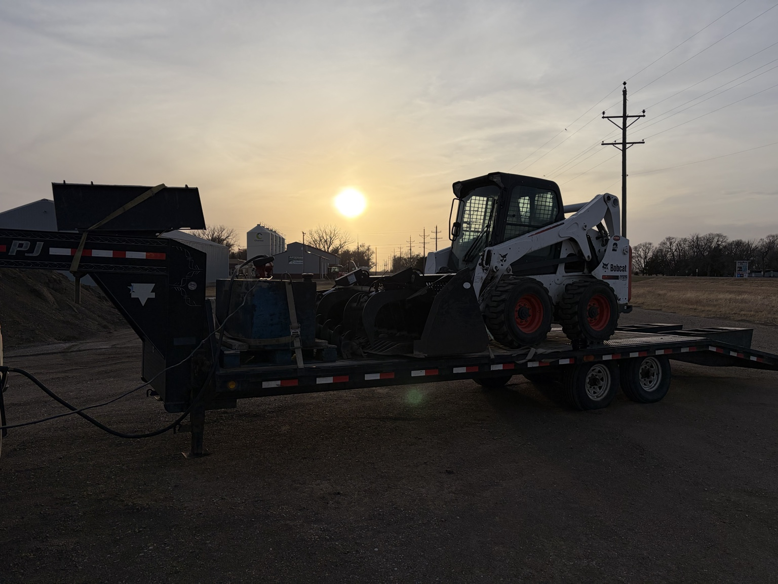 SS Stump Grinding trailer and Bobcat parked at sunset before a job